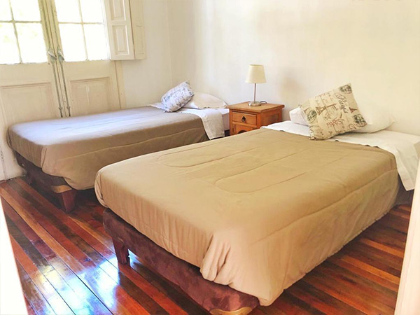 Habitación doble de la residencia con piso de madera noble y ventanas amplias