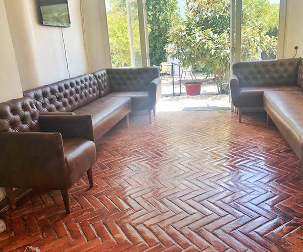 Sala de estar cálida con sofás Chesterfield y piso de madera en Residencia Los Andes