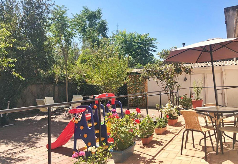 Terraza exterior de Residencia Los Andes con flores, plantas y zona de descanso al sol